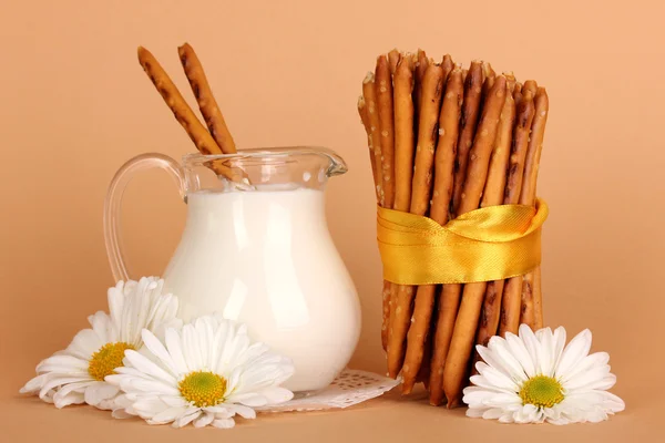 Tasty crispy sticks with pitcher with sour cream on beige background — Stock Photo, Image