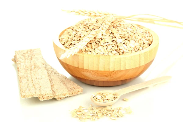 Wooden bowl full of oat flakes with wooden spoon, spikelets and oat biscuits isolated on white — Stock Photo, Image