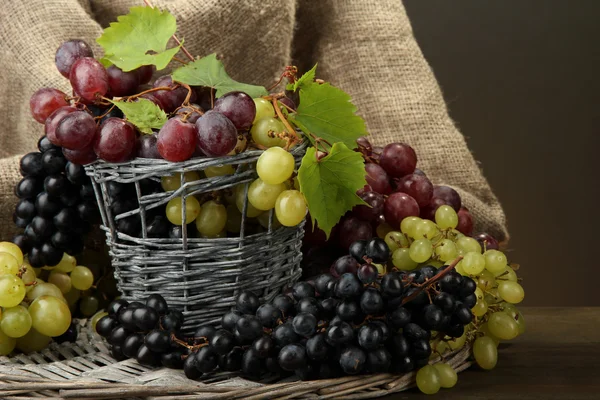 Sortimento de uvas doces maduras em cesto, sobre fundo cinzento — Fotografia de Stock