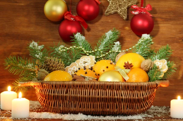 Composición navideña en cesta con naranjas y abeto, sobre fondo de madera —  Fotos de Stock