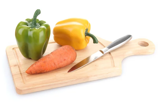 Papryka, marchewka i nóż na deski do krojenia drewniana na białym tle — Zdjęcie stockowe