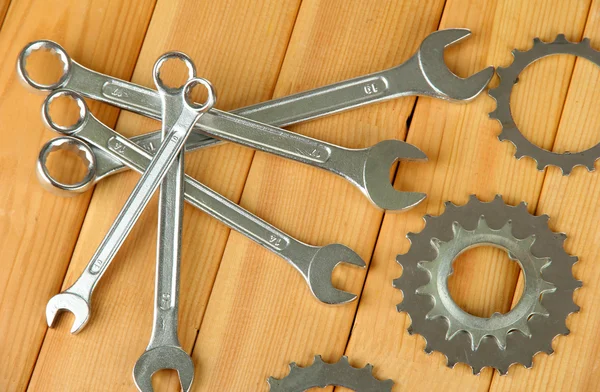 Metal cogwheels and spanners on wooden background — Stock Photo, Image
