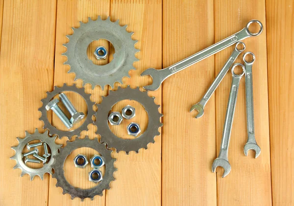 Engrenages de machines, roues dentées métalliques, écrous et boulons sur fond bois — Photo