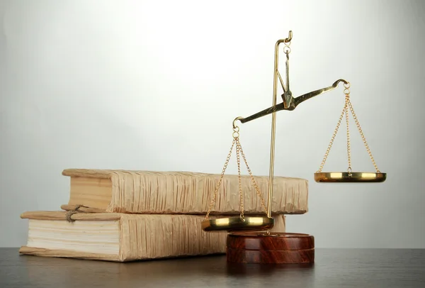 Gold scales of justice and books on grey background — Stock Photo, Image