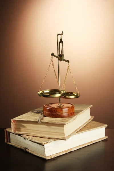 Gouden schalen van Justitie en boeken over bruine achtergrond — Stockfoto