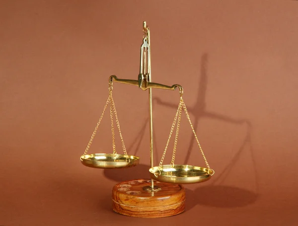 Gold scales of justice on brown background — Stock Photo, Image