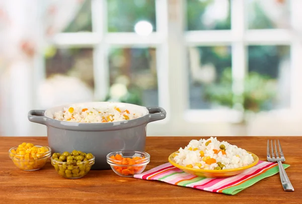 Risotto no pote cinza na mesa de madeira no fundo brilhante — Fotografia de Stock