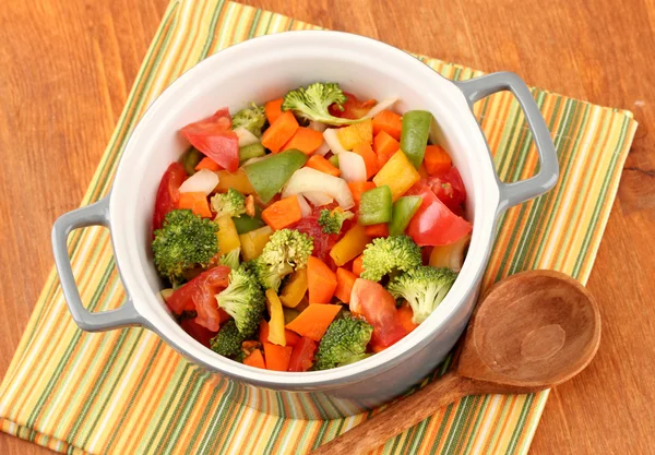 Vegetable stew in gray pot on color napkin on wooden background — Stock Photo, Image