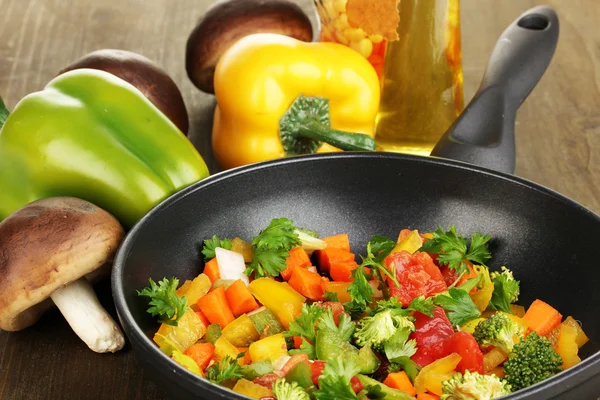 Sliced fresh vegetables in pan with spices and ingredients on wooden table — Stock Photo, Image