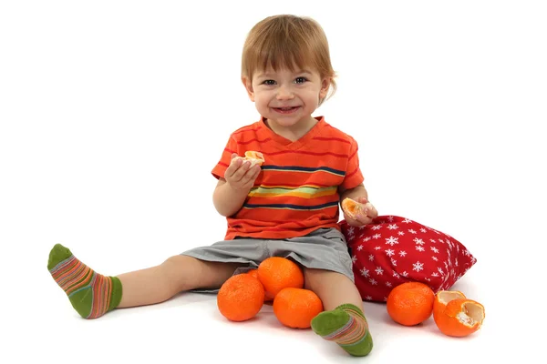 Schattige kleine jongen eten mandarijnen, geïsoleerd op wit — Stockfoto