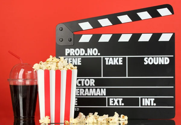 Filmklappbrett, Cola und Popcorn auf rotem Hintergrund — Stockfoto