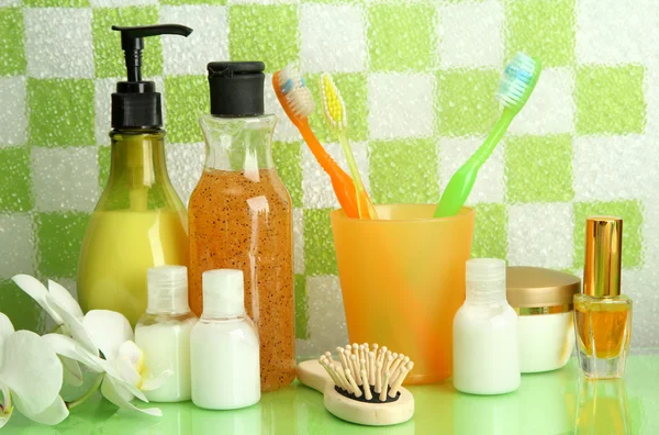 Accesorios de baño en el estante en el baño sobre fondo de pared de baldosas verdes —  Fotos de Stock