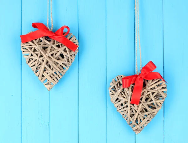 Cuori di vimini con fiocco rosso su sfondo di legno — Foto Stock