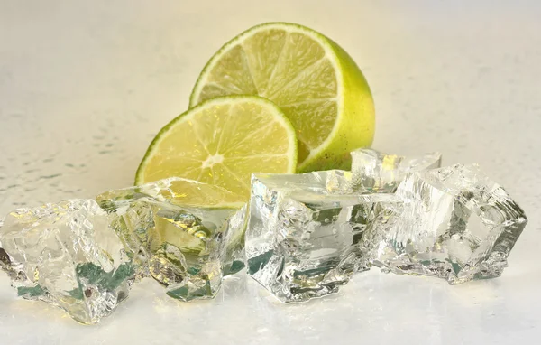 Ice cubes with lime on light yellow background — Stock Photo, Image