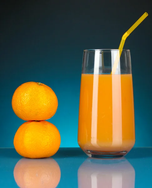 Utsökt tangerine juice i glas och mandariner bredvid den på Mörkblå bakgrund — Stockfoto