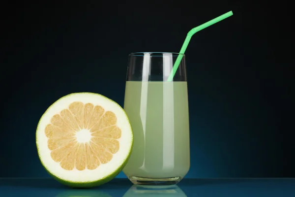 Delicioso jugo de caramelo en vaso y caramelo al lado sobre fondo azul oscuro — Foto de Stock