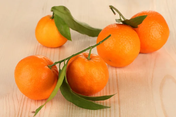 Sladké mandarinky s listy, na dřevěné pozadí — Stock fotografie