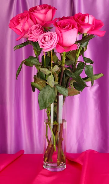 Krásné růžové růže ve váze na pozadí fialové látky — Stock fotografie