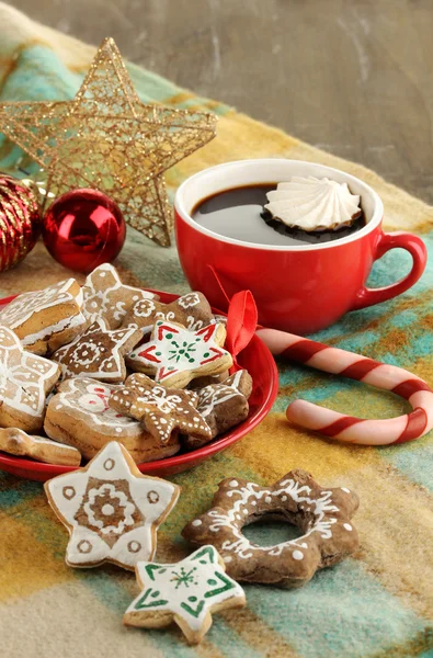 Christmas treats on plate and cup of coffe on plaid close-up — Stock Photo, Image