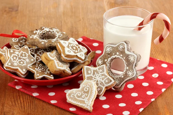 Dulces de Navidad en el plato y vaso de leche en la mesa de madera de cerca — Foto de Stock