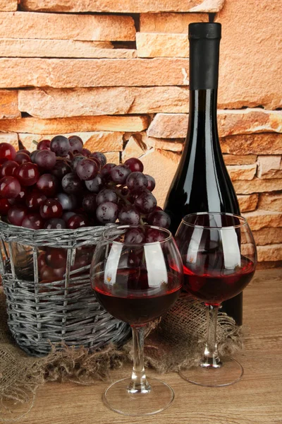 Composition of wine,basket and grapes on table on brick wall background — Stock Photo, Image