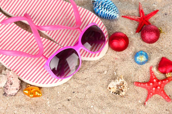 Weihnachtskugeln, Muscheln und Strandaccessoires auf Sand, Nahaufnahme — Stockfoto