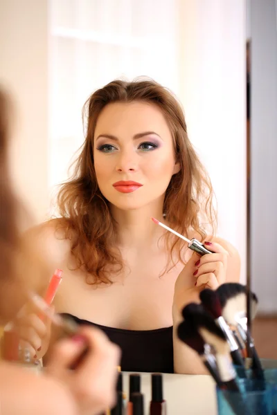 Joven hermosa mujer haciendo maquillaje cerca del espejo —  Fotos de Stock