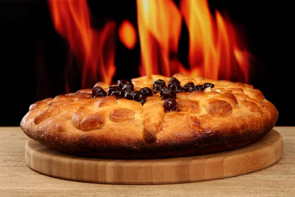 Leckere hausgemachte Torte mit Marmelade, auf Holztisch auf Flammenhintergrund — Stockfoto