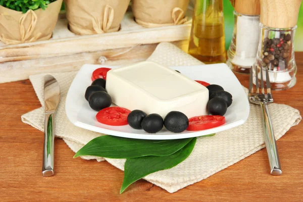 Feta cheese on plate decorated with spices and oil on wooden table on natural background close-up — Stock Photo, Image