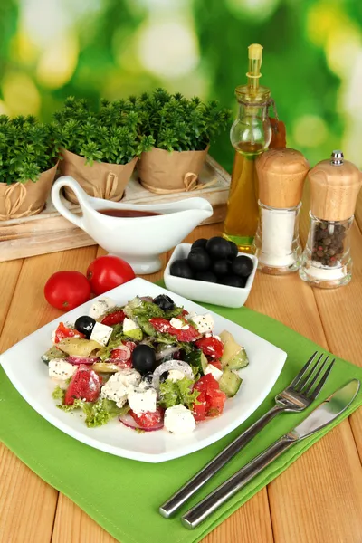 Свежий греческий салат на тарелке на деревянном столе на естественном фоне — стоковое фото