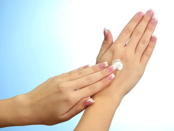 Beautiful woman hands with cream, on blue background — Stock Photo, Image