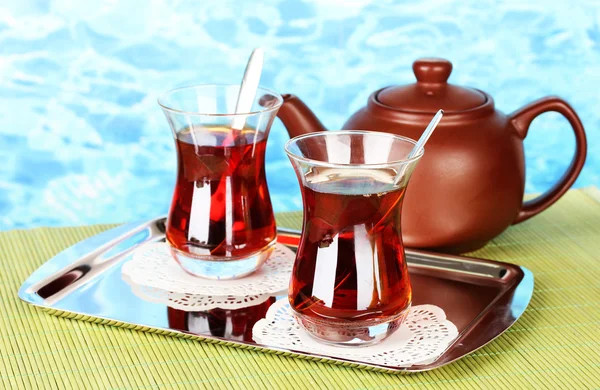 Glass of Turkish tea and kettle on color background — Stock Photo, Image