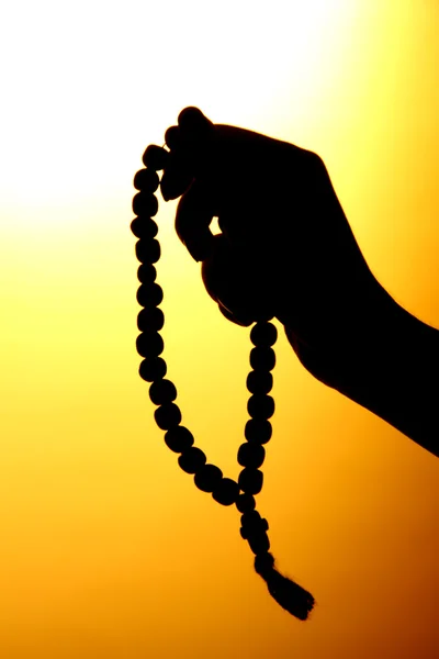 Female hands with rosary, on yellow background — Stock Photo, Image