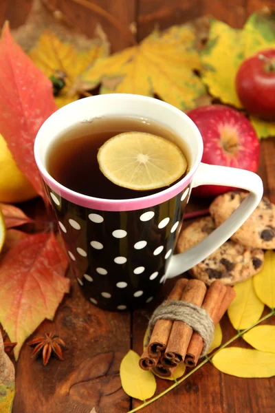 Beker van hete thee en herfst bladeren, op houten achtergrond — Stockfoto