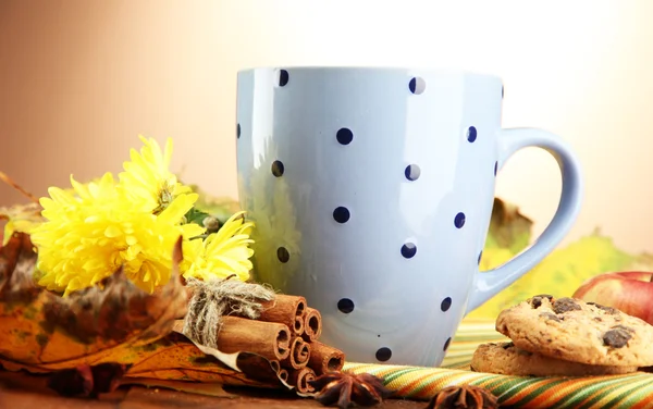 Šálek horkého čaje a podzimní listí, na hnědém pozadí — Stock fotografie