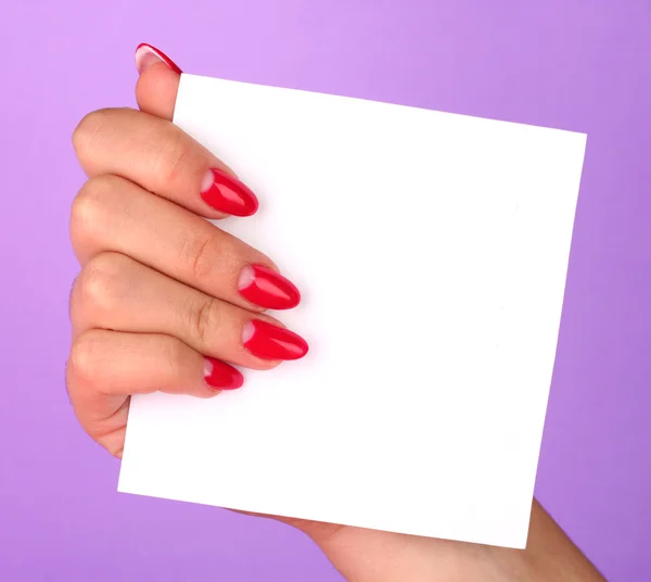 Mano della donna che tiene carta bianca su sfondo a colori — Foto Stock