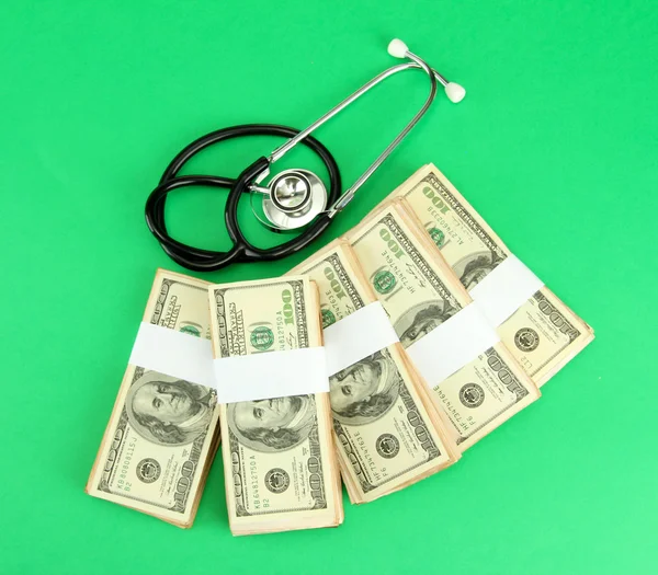 Pojetí zdravotní náklady: stetoskop a dolarů na zeleném pozadí — Stock fotografie