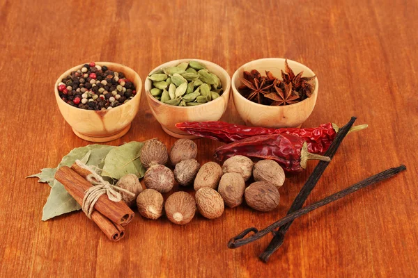 Nootmuskaat en andere specerijen op houten achtergrond — Stockfoto