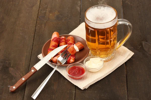 Cerveza y embutidos a la parrilla sobre fondo de madera — Foto de Stock