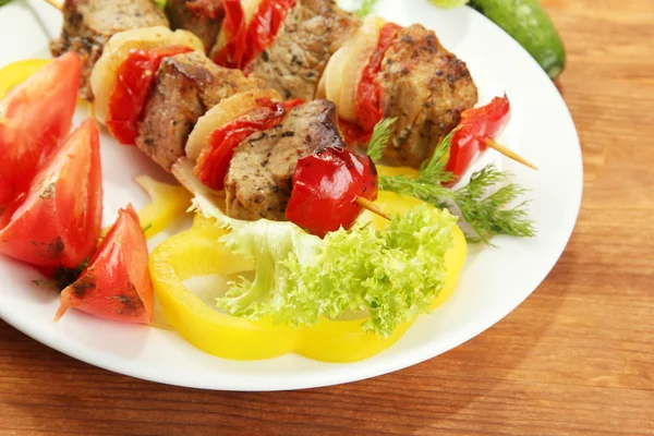 Sabrosa carne a la parrilla y verduras en pincho en el plato, en la mesa de madera — Foto de Stock