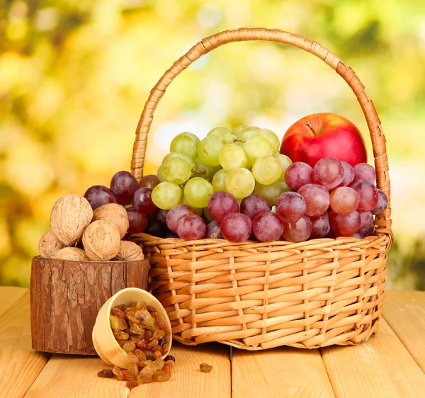 Grape in basket with nuts on wooden table — Stock Photo, Image
