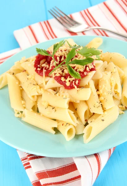 Piatto di pasta rigatoni con salsa di pomodoro sul tavolo di legno blu da vicino — Foto Stock