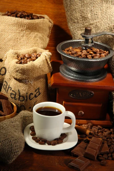 Młynek do kawy i filiżanka kawy na brązowym drewnianym tle — Zdjęcie stockowe