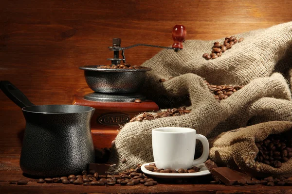 Coffee grinder, turk and cup of coffee on brown wooden background — Stock Photo, Image