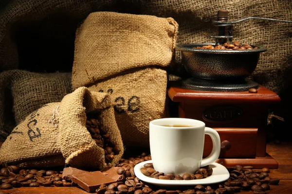 Moulin à café et tasse de café sur fond de toile de jute — Photo