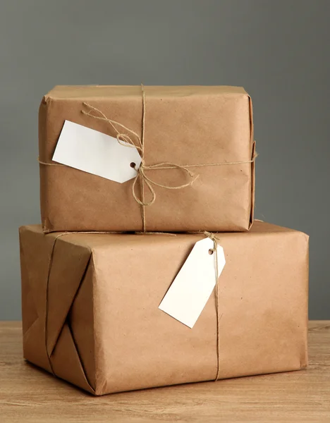 Kutuları gri arka plan üzerinde ahşap masa hakkında kraft kağıt paketler — Stok fotoğraf
