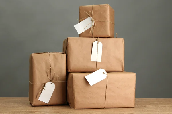 Parcels boxes with kraft paper, on wooden table on grey background — Stock Photo, Image