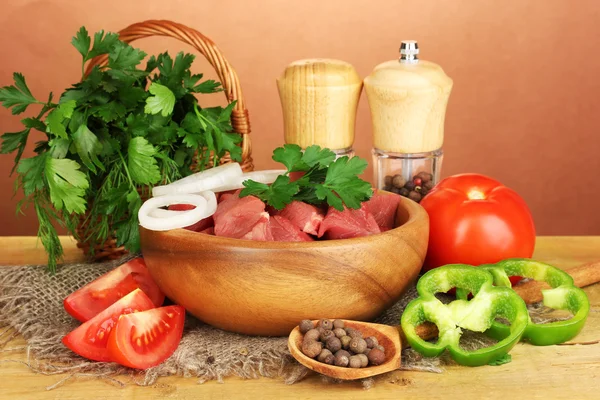 Viande de bœuf crue aux herbes et épices sur table en bois sur fond brun — Photo