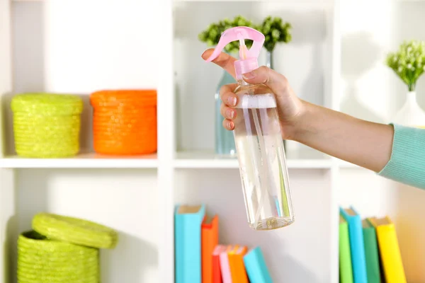 Sprayed air freshener in hand on white shelves background — Stock Photo, Image