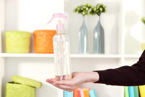 Sprayed air freshener in hand on white shelves background — Stock Photo, Image